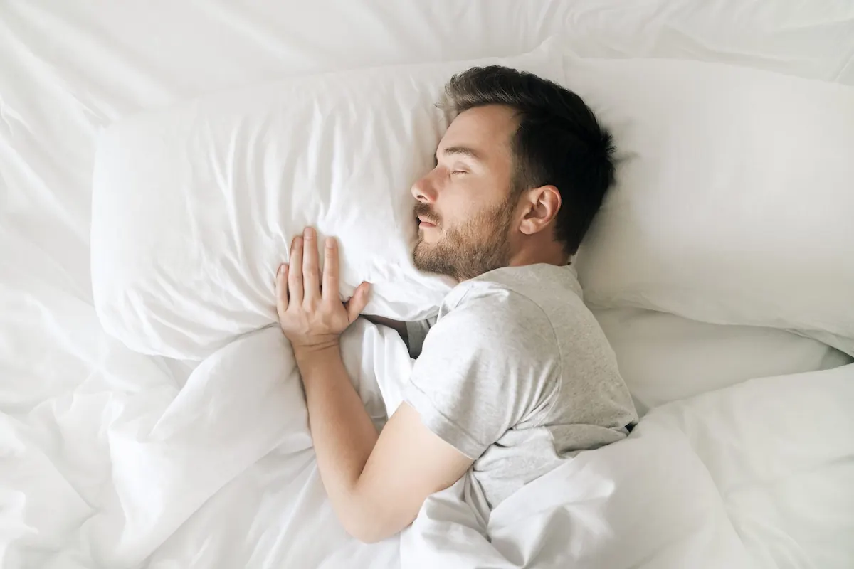 Man resting in bed, representing wellness days and recovery