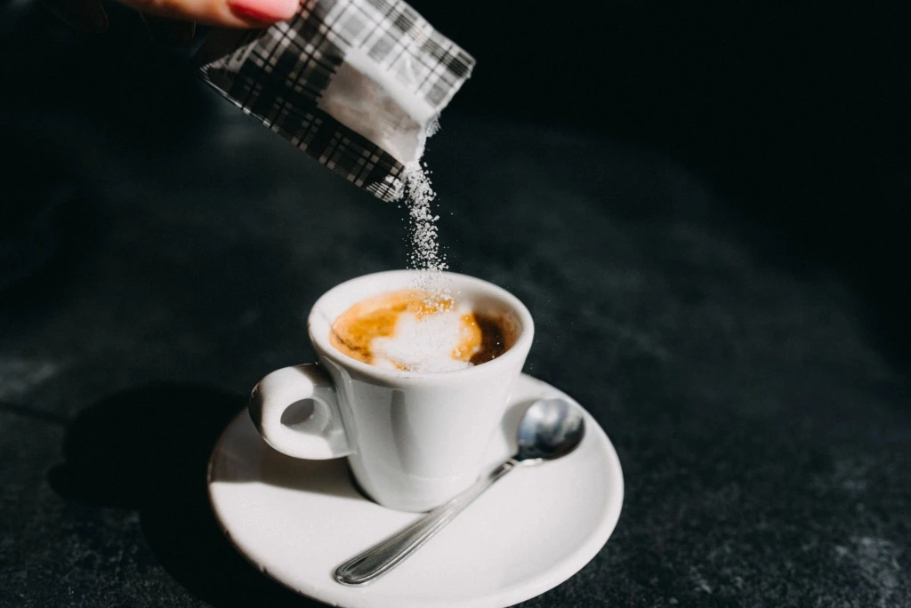 Granulated xylitol sweetener being added to a cup of coffee